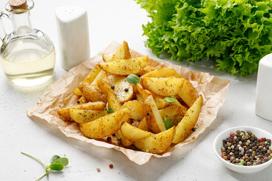 Baked potato wedges on craft paper. Roasted potatoes with herbs, spices and greens. Dinner idea.
