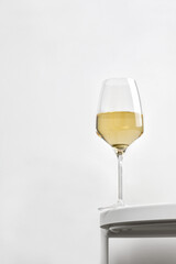 White wine in rich glass on a white round table. Minimalism. Elegant