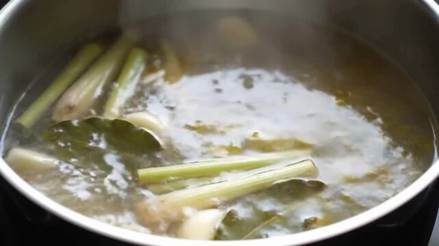 A close-up of fragrant herbs and spices boiling in a pot of water to create a flavorful broth. soto