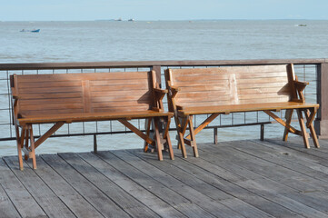 Two empty wooden benches invitingly face the calm sea horizon