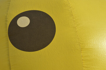 Bright yellow inflatable duck face close-up with red beak detail