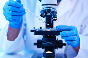 A young woman in a lab coat conducts precise experiments, peering through a microscope while transferring liquid reagents in a well-equipped laboratory.