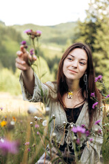 Portrait of young woman sitting in wildflowers on a sunny summer day.