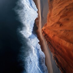 Vertical Aerial Shot of Coastal Border Where Fiery Red Desert Meets Cold Blue Ocean Water