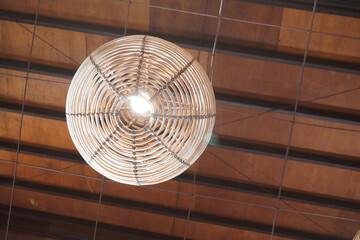 Warm woven pendant light illuminates natural wood ceiling creating cozy ambiance