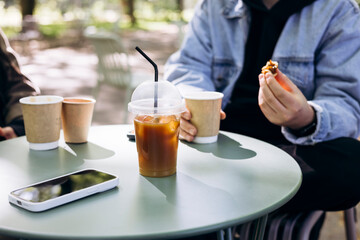 A group of friends drinking coffee on the terrace of a coffee shop in the yard.