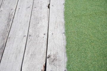 Weathered wooden planks meet vibrant green turf in a textured outdoor scene