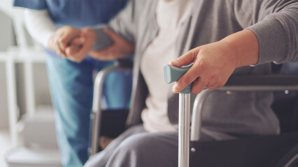 The nurse is helping the old patient with a cane