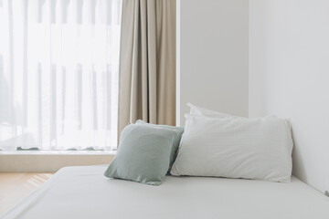 Bright bedroom featuring simple bed design, soft cushions, and daylight filtering through layered curtains. Tranquil atmosphere with clean lines and light tones.Minimalist bed with white linens 