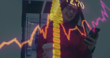Standing Asian woman holding smartphone and coffee cup in office corridor with stock market chart
