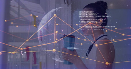 Analyzing Asian woman engaging with data overlay behind glass wall, with blue insulated travel mug