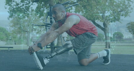 Leaning athlete wearing sportswear extending right leg on park rubber surface, with prosthetic leg