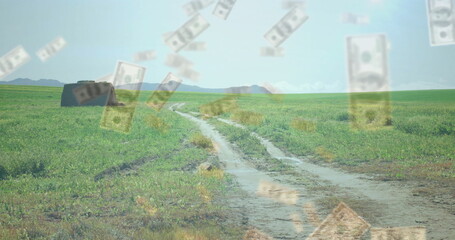 Small weathered shack standing in grassland near winding dirt road, with floating US dollar bills