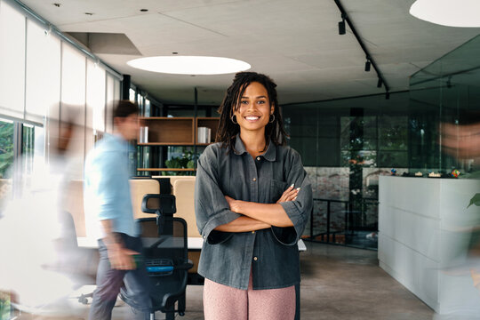 Success woman with diverse employees walking in background, business coworking space - Powered by Adobe