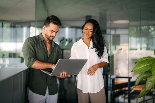 Two happy diverse multiethnic business team people working, talking in corporate office