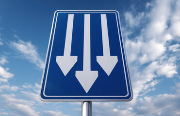 Blue road sign with three white arrows pointing downward against cloudy sky, indicating multiple lanes