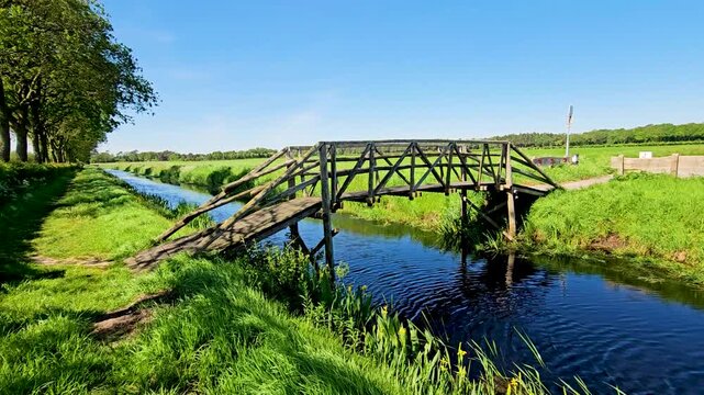 Wooden bridge crossing bright blue body of water or stream. Bridge crossing small river in nature hiking landscape.