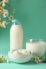 Fresh milk, mozzarella balls and flowers on turquoise background. Dairy products