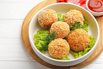 Delicious fried croquette balls with parsley and lettuce on white wooden table, closeup