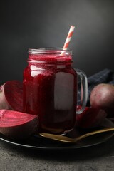 Superfood. Refreshing smoothie in mason jar and beetroot on grey textured table against dark background, closeup