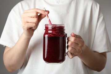 Superfood. Woman with mason jar of tasty smoothie against grey background, closeup