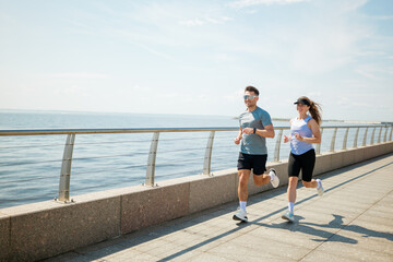 Couple enjoying a morning run along the scenic waterfront promenade while embracing an active...