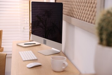Stylish workplace with wooden desk, computer and stationery at home office, closeup. Interior design