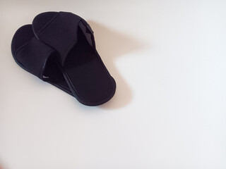 Pair of black disposable hotel guest slippers isolated on white background.