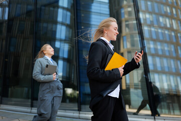 Professionals walking with purpose outside a modern office building in the bustling city during...