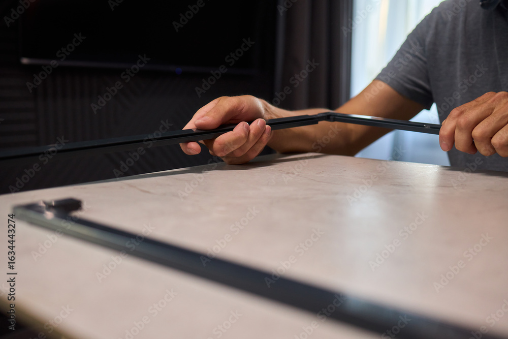 Poster hand assembling a frame on a beautiful and modern table in a creative workspace