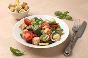 Delicious salad with croutons, vegetables and basil on wooden table, closeup