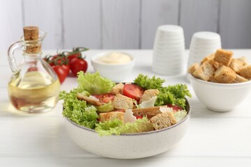 Delicious salad with croutons and ingredients on white wooden table, closeup
