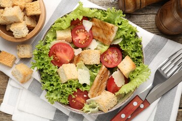 Delicious salad with croutons served on wooden table, flat lay