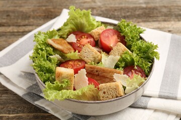 Delicious salad with croutons, chicken, vegetables and cheese on wooden table, closeup