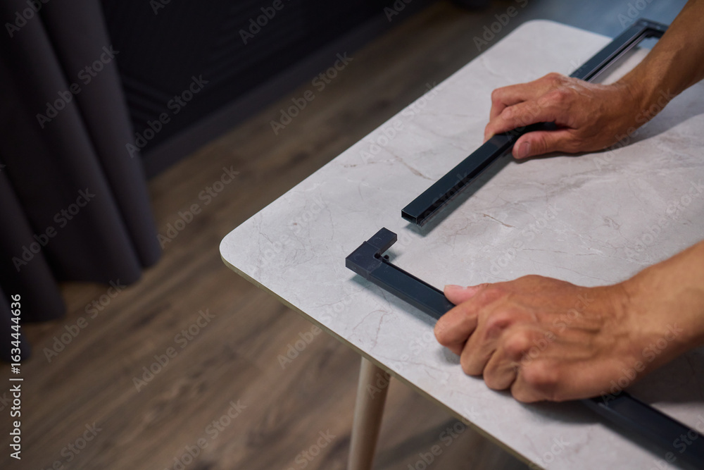 Poster hand assembling a frame on a beautiful and modern table in a creative workspace