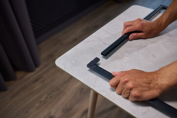 Hand Assembling a Frame on a Beautiful and Modern Table in a Creative Workspace