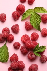 Tasty fresh ripe raspberries and leaves on pink background, flat lay