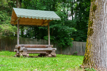 recreation area in a forest, gazebo with a bench and table in the middle of a forest in a clearing