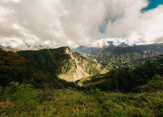 Dramatic mountain range with lush green vegetation and cloudy sky. Scenic landscape view.