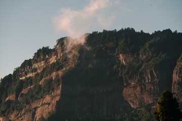 Dramatic mountain landscape with a hazy mist rising from the cliffs at dusk.