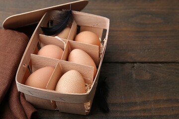 Raw chicken eggs in egg tray on wooden table, closeup. Space for text