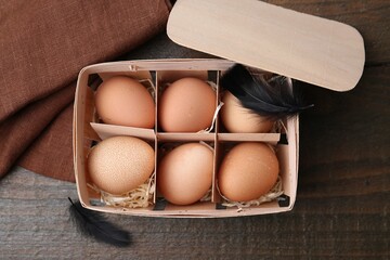 Raw chicken eggs in egg tray on wooden table, top view