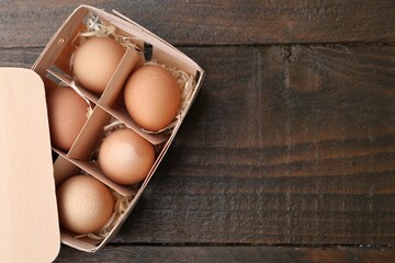 Raw chicken eggs in egg tray on wooden table, top view. Space for text