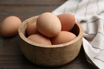Raw chicken eggs in bowl on wooden table, closeup