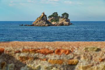 Beautiful seascape with sea view and islands with small church on top of cliff at sunset. The Sveta Nedelya and Katic Islands, near Petrovac city, Montenegro