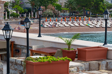 architecture of resort town and beach by sea against backdrop of mountains covered with forest, Petrovac city, Montenegro