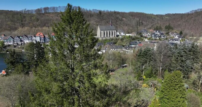 village with Beyenburg chappel cathedral and dam, surrounded by woods, blue sky and green hills