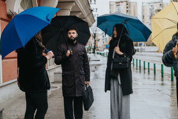 A group of individuals holding umbrellas having an outdoor discussion in a rainy urban setting. The...