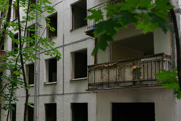 An old panel house slated for demolition: windows without glass, an old rusty balcony