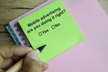 Mobile advertising are you doing it right write on sticky notes isolated on Wooden Table. A person...